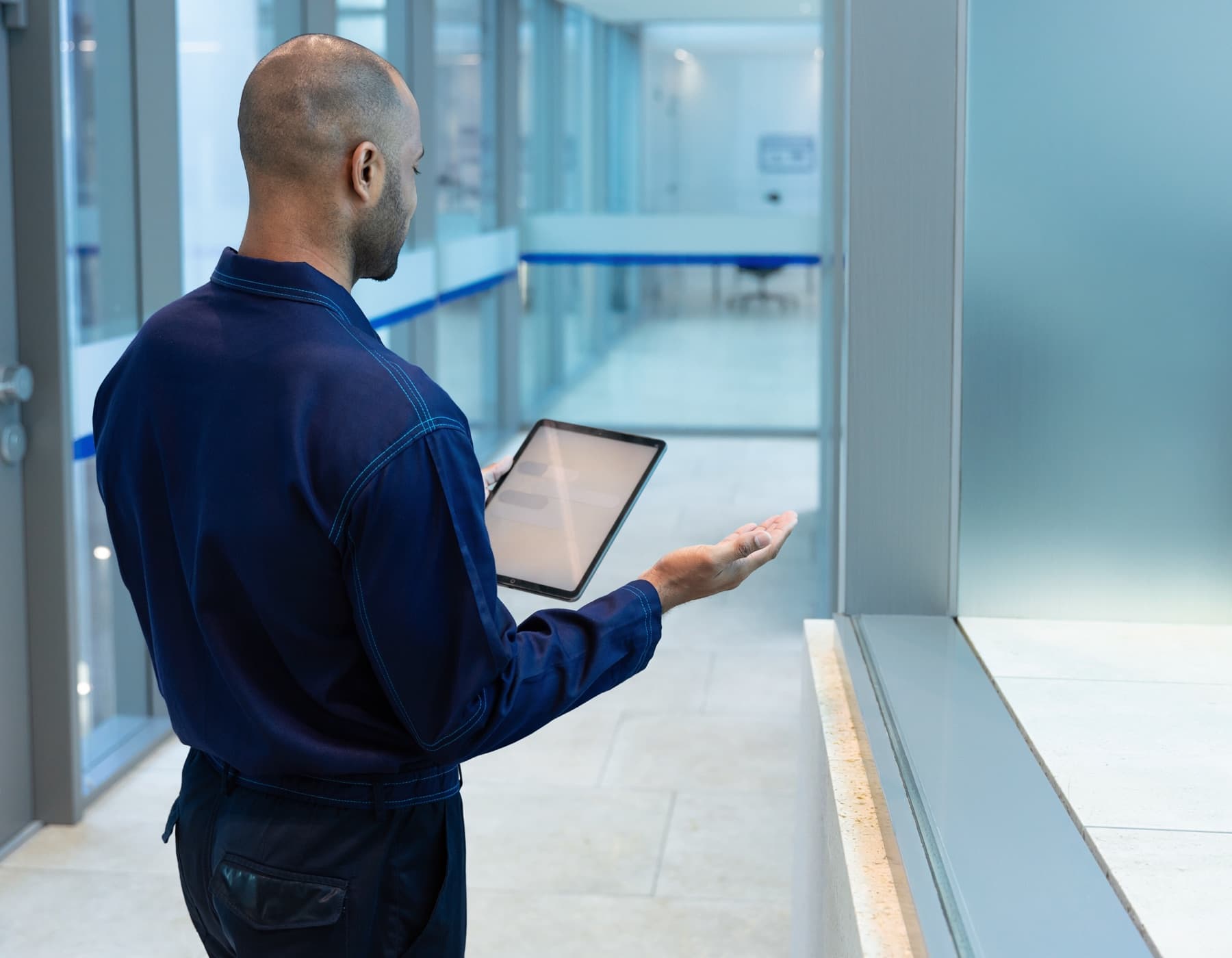 Verantwoordelijke met tablet controleert tijdens een rondgang een oppervlak in een kantoorgang.